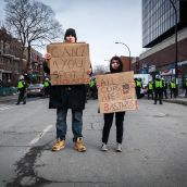 A couple of protesters holding signs in front of Montreal Police.