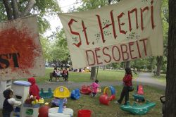 Children play under a provocatively-worded sign, reading "St. Henri disobeys" (Sophie Blais)